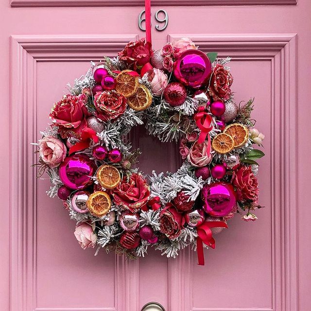 pink and orange holiday wreath against a pink door