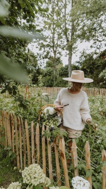 woman gardening in hat behind picket fence