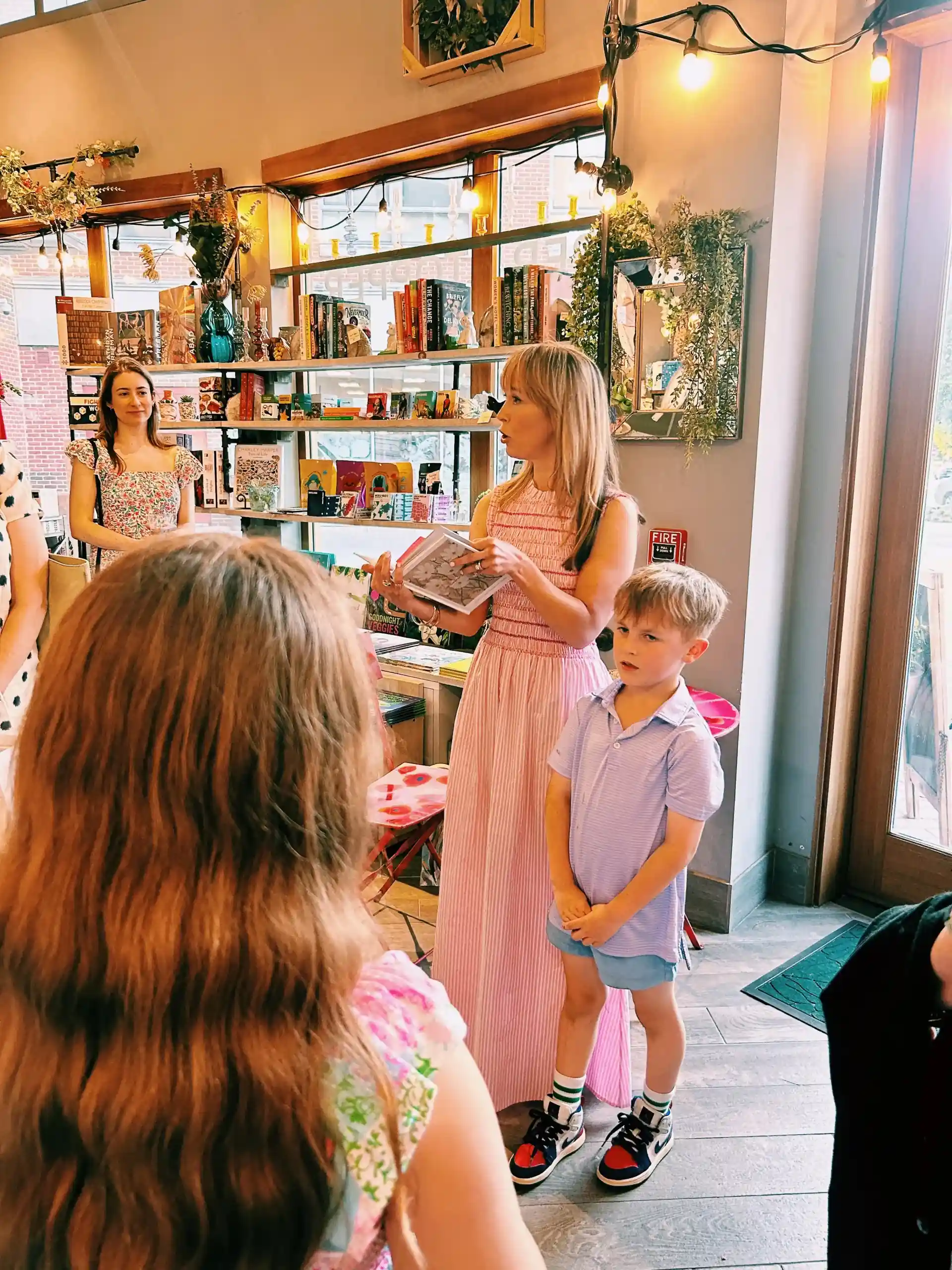 Jen Shoop holds a copy of Small Wonders while speaking at a book event at Proper Topper.
