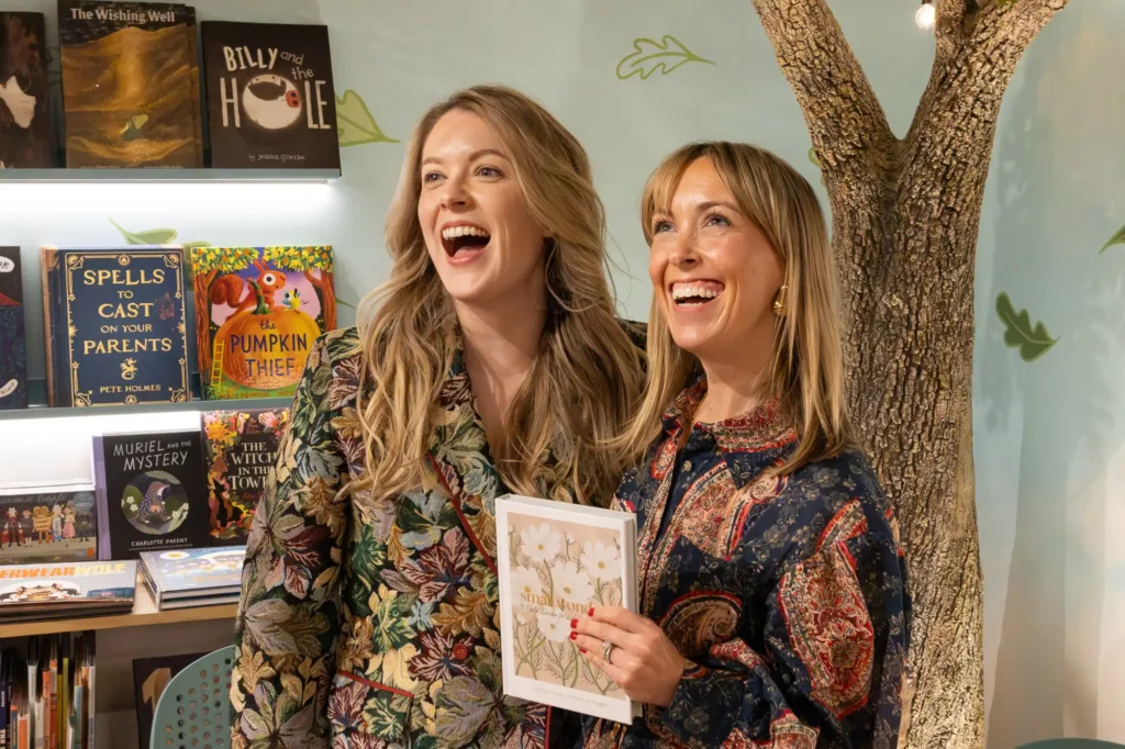 Jacqueline Bond and Jen Shoop smiling together, with Jen holding Small Wonders, at Old Town Books.