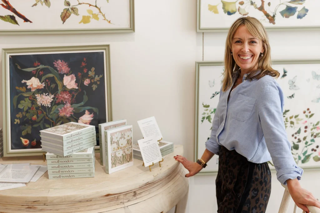 Jen Shoop beside a Small Wonders book display and framed floral artwork in Inslee Fariss’s Raleigh studio.